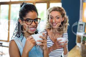 Portrait of female friends smiling while having coffee