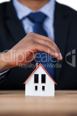 Businessman protecting house model with hands