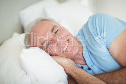 Portrait of happy senior man lying on bed