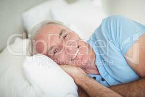 Portrait of happy senior man lying on bed