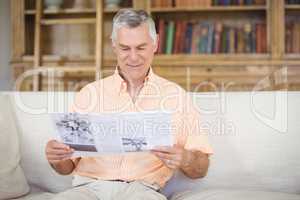 Senior man reading newspaper in living room