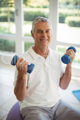 Senior man exercising with dumbells at home
