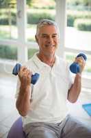 Senior man exercising with dumbells at home