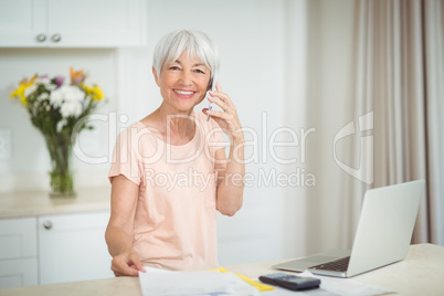 Portrait of senior woman talking on mobile phone in kitchen