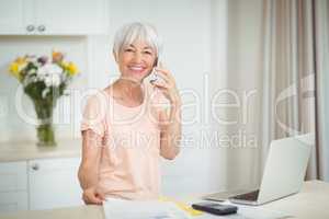 Portrait of senior woman talking on mobile phone in kitchen