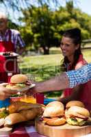 Father passing plate of burger to son in park