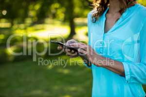 Mid section of woman using mobile phone in park