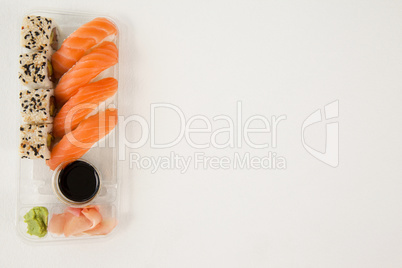 Nigiri and uramaki served with soy sauce in plastic box