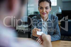 Business executive giving visiting card to man during interview