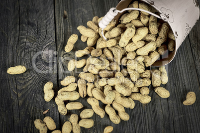 Loose peanuts in the shell on a gray wooden surface, vintage ton