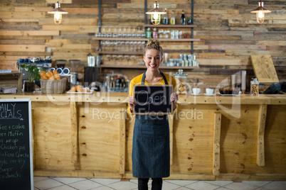 Smiling waitress standing with open sign board in cafe
