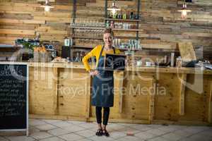 Smiling waitress standing with open sign board in cafe