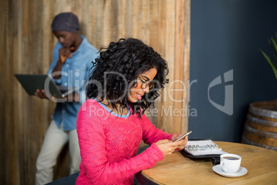 Woman using mobile phone while having a coffee in cafÃ?Â©