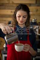 Smiling waitress making cup of coffee