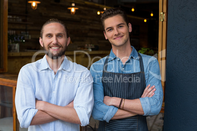 Portrait of man and waiter standing with arms crossed