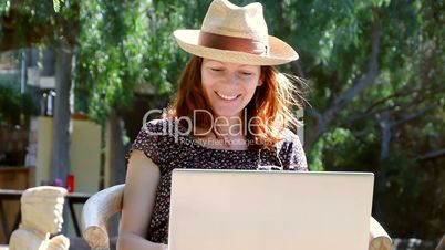 Woman sits in the garden enjoying a conversation on her laptop in the sun