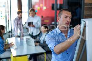 Attentive businessman writing on flip chart