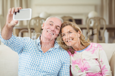 Senior couple taking a selfie on mobile phone in living room