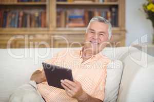 Smiling senior man using digital tablet in living room