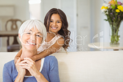 Portrait of smiling granddaughter embracing her grandmother in living room