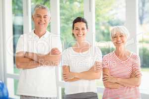 Female trainer and senior couple standing together with arms crossed