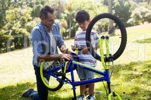 Son and father repairing their bicycle in park