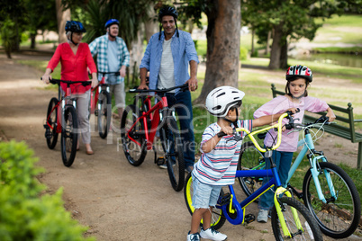 Multi-generation family walking with bicycle in park