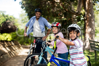Father and children standing with bicycle in park