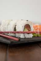 Uramaki and sashimi sushi served with chopsticks in black stone slate