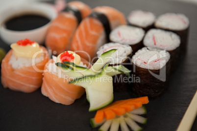 Set of assorted sushi served on black stone slate with soy sauce and chopsticks