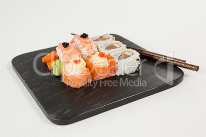 Uramaki and nigiri sushi served with chopsticks in black stone slate