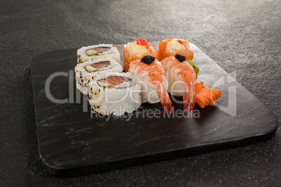 Uramaki and nigiri sushi served in black stone slate