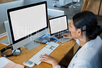 Businesswoman working over computer and laptop