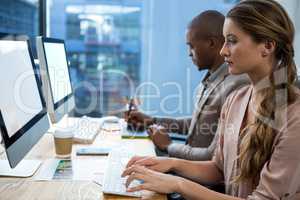 Graphic designer working at desk with colleague