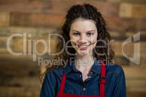 Portrait of smiling waitress standing against wooden wall