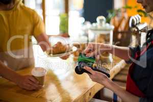 Customer making payment through credit card at counter in cafÃ?Â©