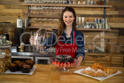 Portrait of waitress serving cake at counter in cafÃ?Â©