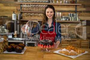 Portrait of waitress serving cake at counter in cafÃ?Â©