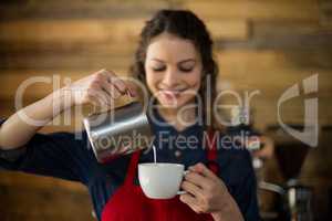 Smiling waitress making cup of coffee