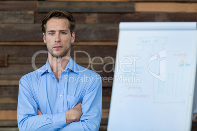 Male business executive standing with arms crossed in office