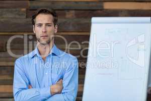 Male business executive standing with arms crossed in office