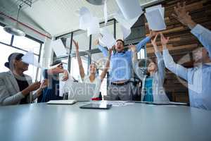 Team of graphic designers throwing documents up in air