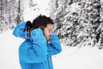 Skier wearing hooded jacket on snowy mountains