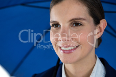 Smiling businesswoman holding blue umbrella