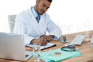Doctor writing on clipboard at desk