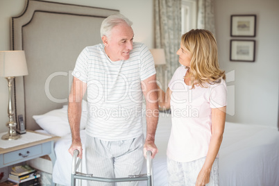 Senior woman helping man to walk with walker