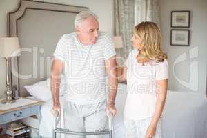 Senior woman helping man to walk with walker