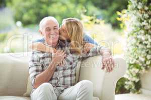 Senior woman kissing man on cheek in living room