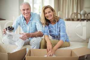Smiling senior couple unpacking carton boxes in living room