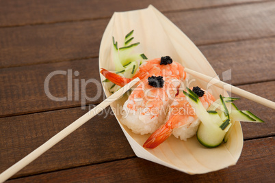 Three nigiri sushi served with chopsticks in wooden boat plate